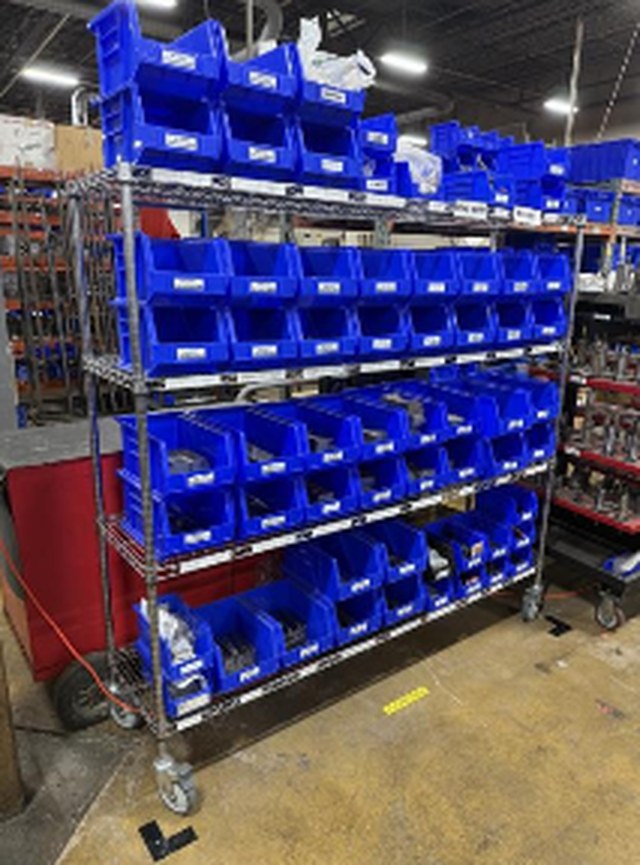 A rolling wire rack filled with blue bins